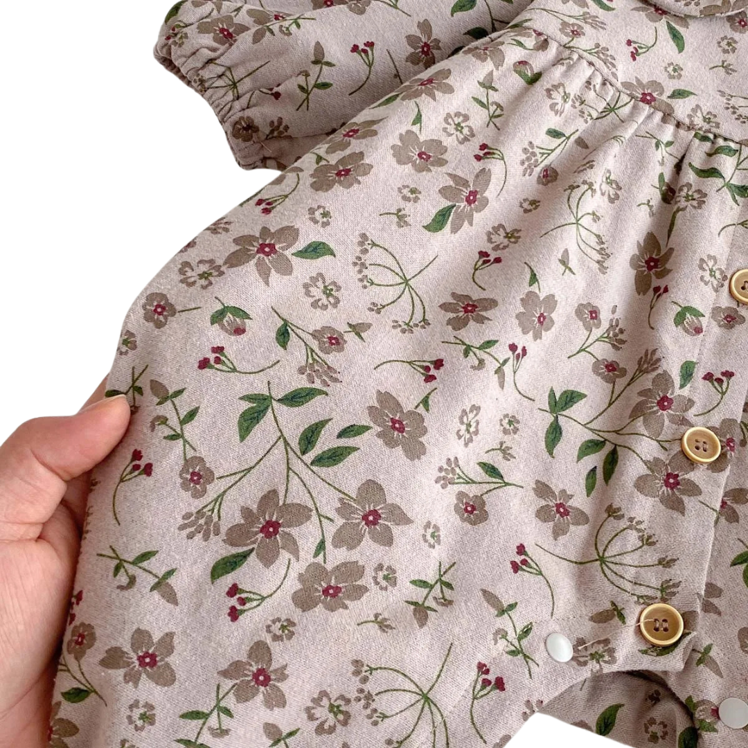 Close-up of a hand holding the soft cotton-blend fabric, highlighting the vintage mauve base color and earthy floral print.