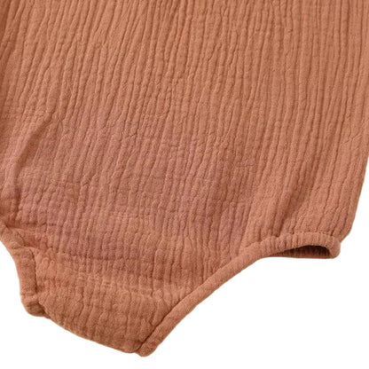Zoomed view of the comfort-fit soft elastic leg band binding and double-needle bottom stitching on a terracotta muslin romper.