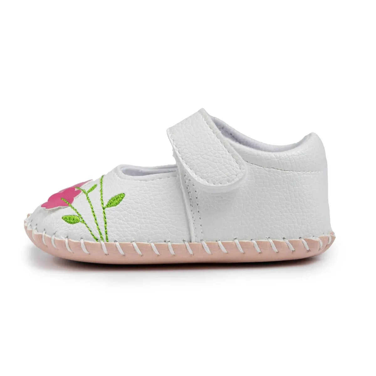 Side profile of a single white baby girl shoe showing the flexible soft sole, pink floral stitching, and strap closure.