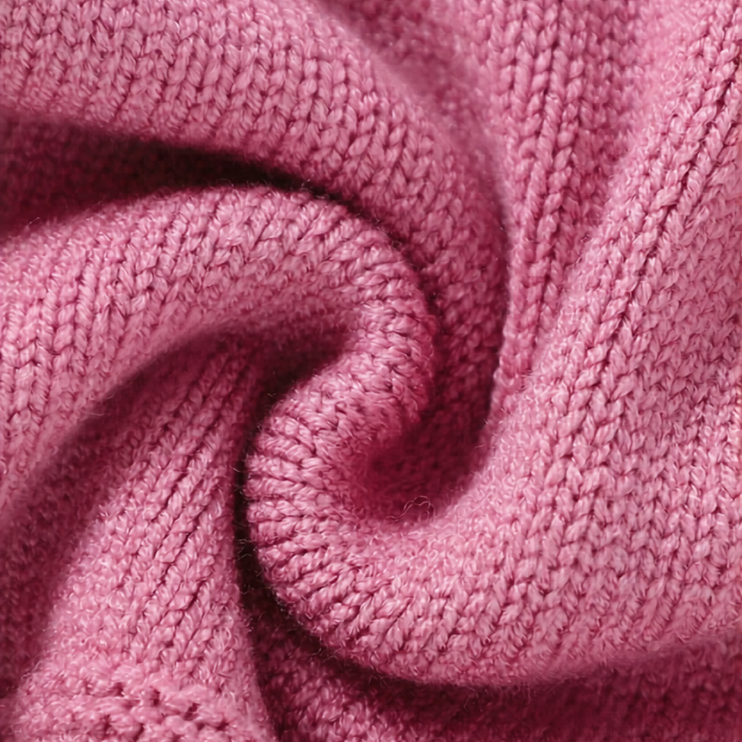 Macro close-up showing the soft, warm viscose yarn texture of a pink knitted toddler dress.