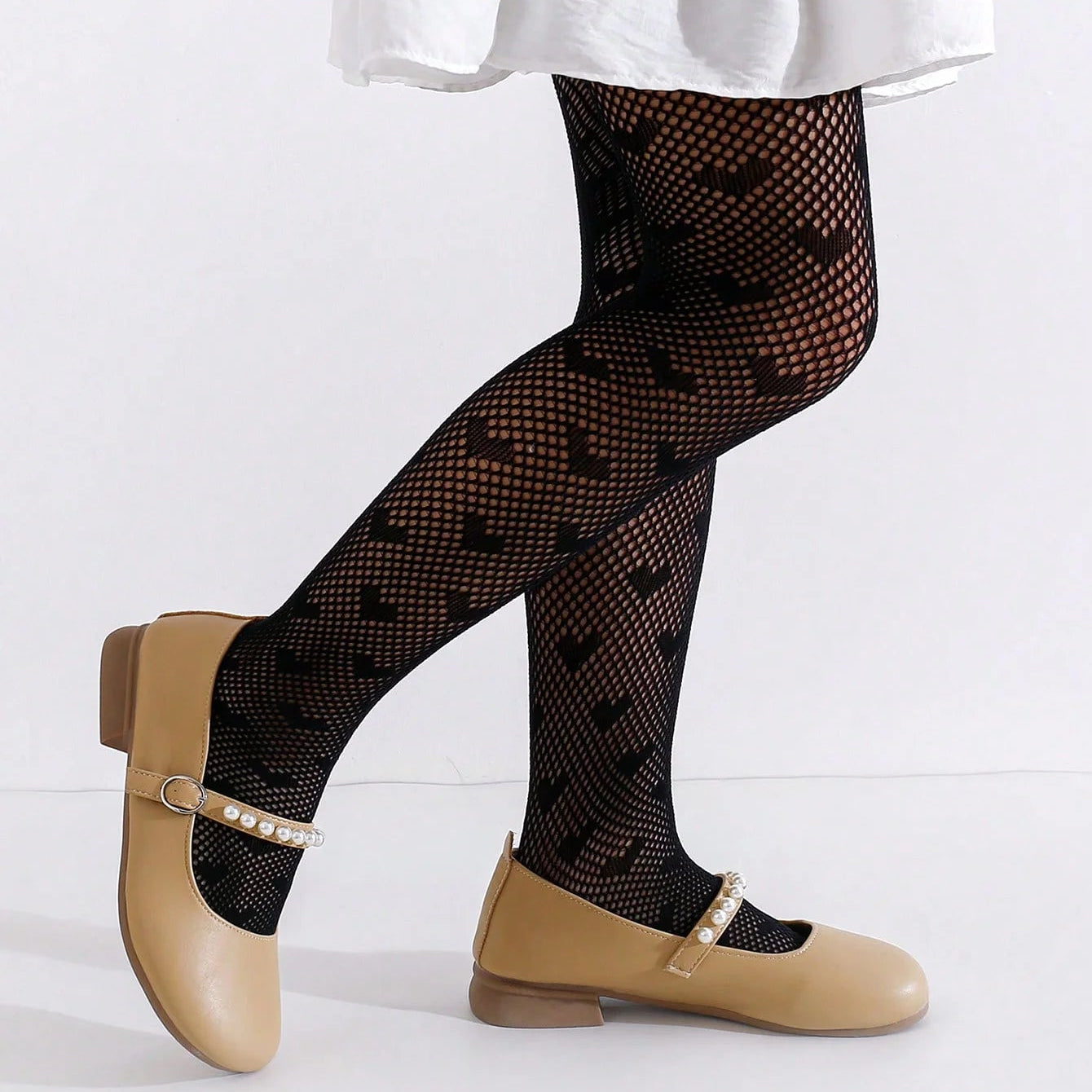 toddler legs wearing black heart patterned tights and tan shoes