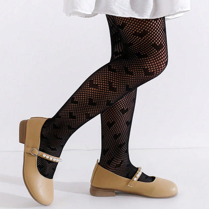 toddler legs wearing black heart patterned tights and tan shoes