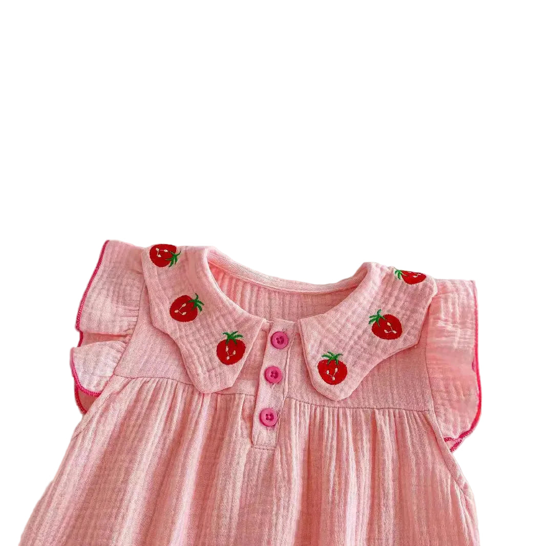 Close-up shot of the pink muslin baby romper showing the flutter sleeves and the embroidered red strawberries on the Peter Pan style collar.