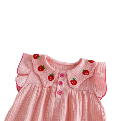 Close-up shot of the pink muslin baby romper showing the flutter sleeves and the embroidered red strawberries on the Peter Pan style collar.