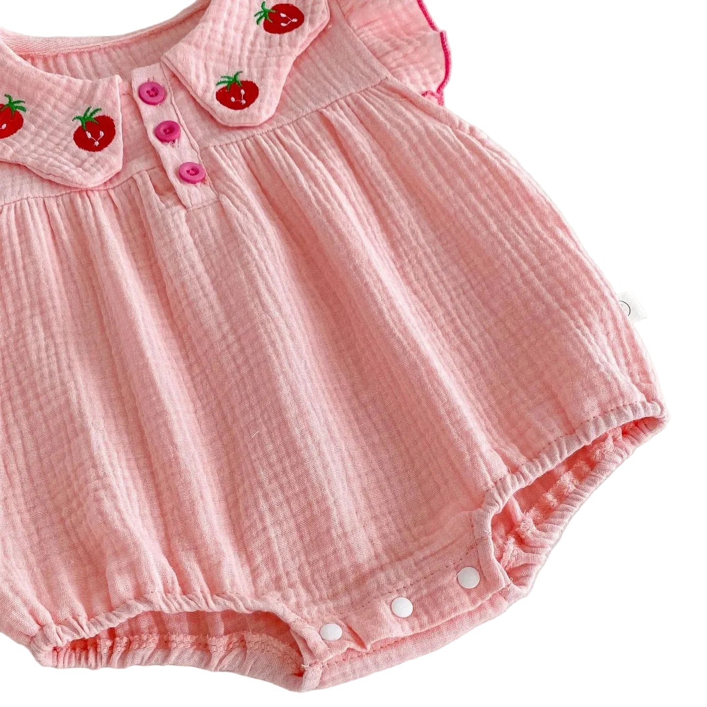 An angled close-up view of the lower half of the pink strawberry romper, displaying the elasticated leg cuffs and snaps for easy diaper changes.