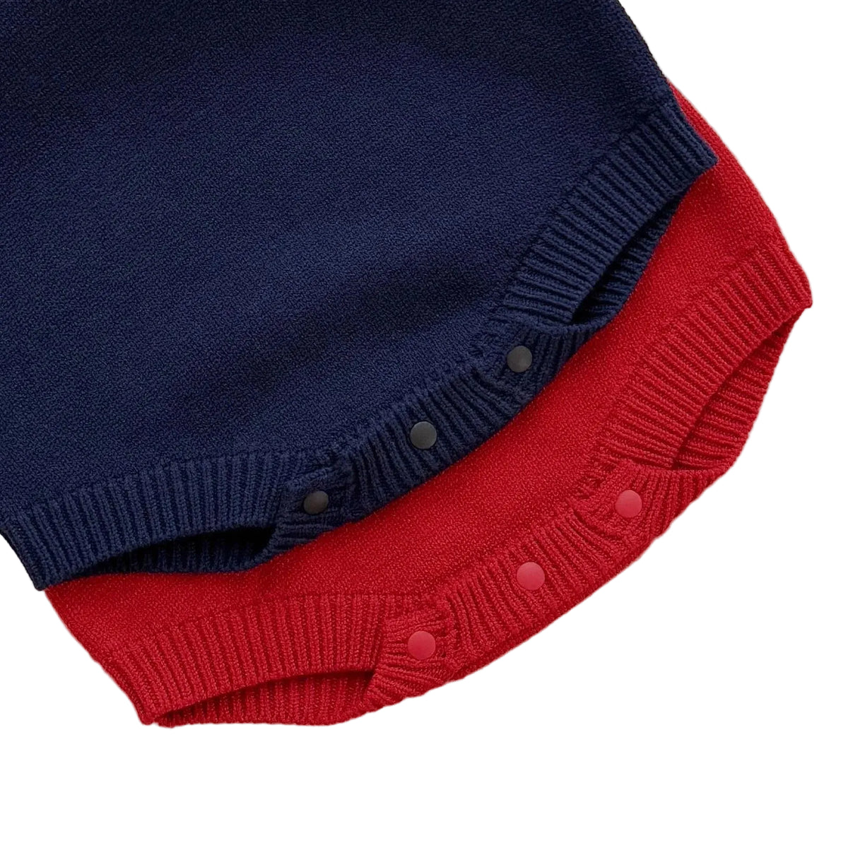 Close-up of the secure bottom button snap closures on the ribbed knit material of the navy and red baby girls sweater rompers.