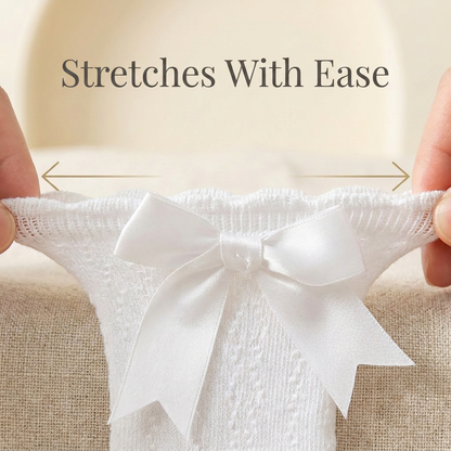 Hands stretching the high-elastic ruffle cuff of a white baby girl dress sock to demonstrate its flexible, non-restrictive fit.