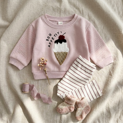 Aesthetic flat lay of the matching coordinates styled on a cozy blanket with matching pink shoes, ruffle socks, and a decorative dried flower.