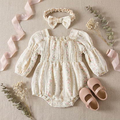 Styled flat lay of a fairytale princesscore baby girl romper and headband set, accessorized with pink ribbons, dried flowers, and small baby shoes.