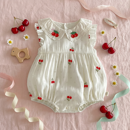 White baby romper with cherry pattern on a pink background