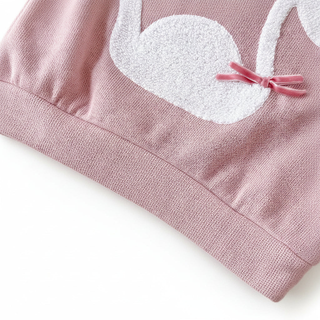 Zoomed-in macro shot of the textured white towel-stitch swan embroidery featuring a small pink velvet ribbon bow attached to the wing.