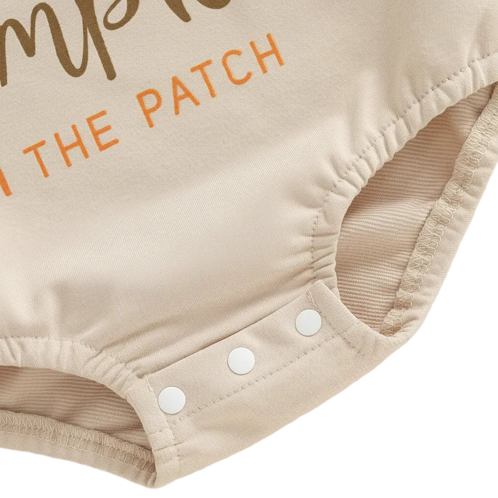 Close-up of the three bottom snap closures on the beige baby sweatshirt bubble romper designed for easy diaper changes.
