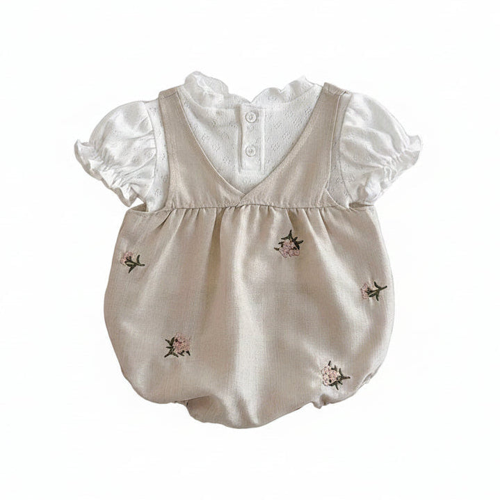 Back view of the complete Sweet Pea 2-piece baby girl floral embroidered camisole romper layered over the white puff-sleeve bodysuit.