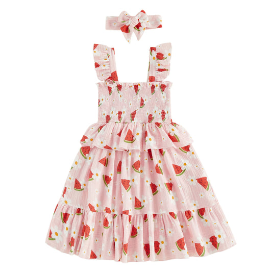 Toddler girl summer dress in Sweet Watermelon & Daisy print featuring a smocked bodice, tiered ruffle skirt, and matching bow headband.