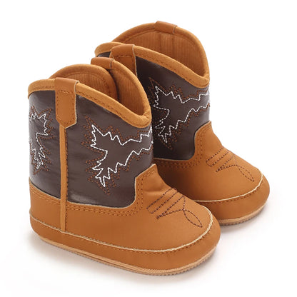 Pair of tan and brown infant winter western shoes with white embroidery.