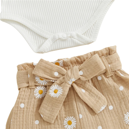 Close-up of the taupe baby girl daisy print pants showing the elastic waistband with front tie and the bottom snaps of the ribbed bodysuit.