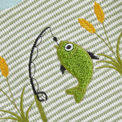 Close-up detail of the textured, raised green bass applique and embroidered fishing pole with yellow cattails on the baby bodysuit.