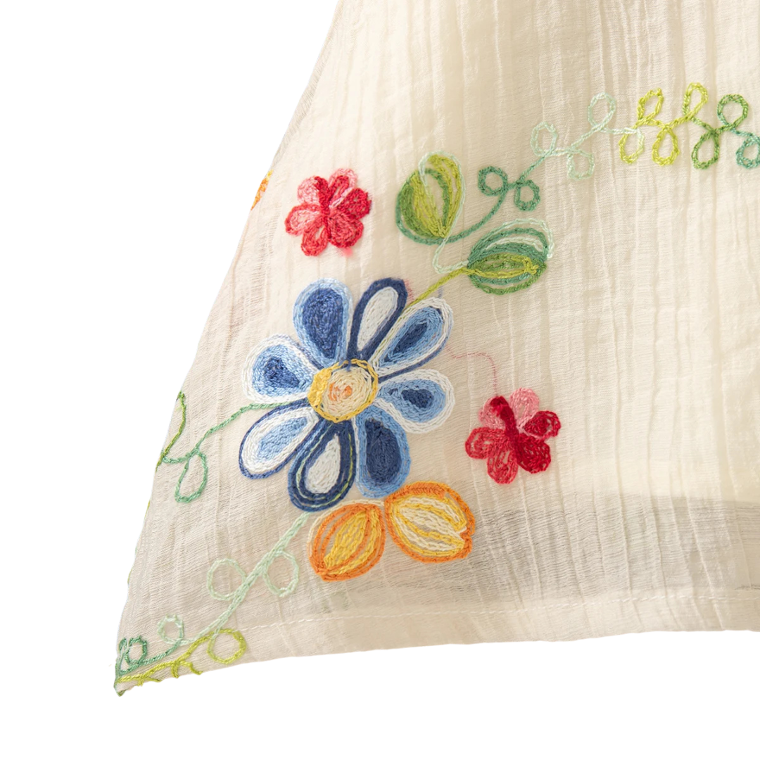 Close-up view of the breathable textured tatting fabric and side embroidery detail of the ivory summer sundress.