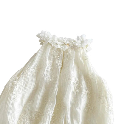 Detailed view of the back of the crinkled gauze fabric and tufted floral embroidery baby romper.