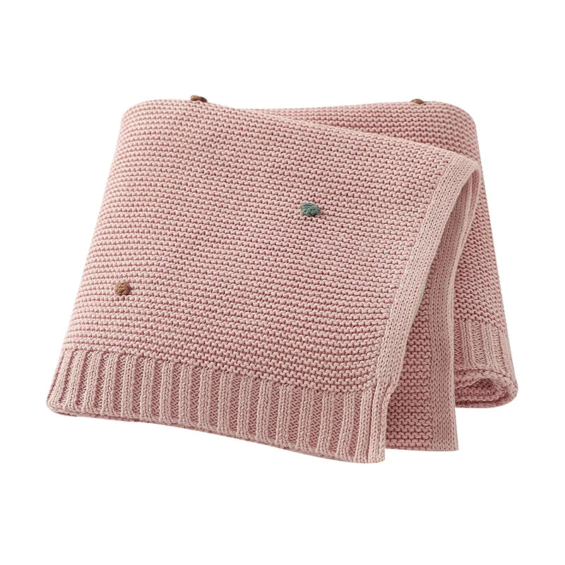 Petal Pink breathable cotton knit baby blanket with decorative dots, perfect for a nursery or stroller.