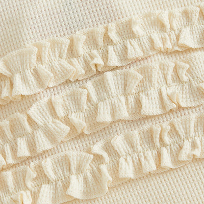 Close-up of the three-tiered ruffle design on the back of the cream ribbed cotton baby romper.