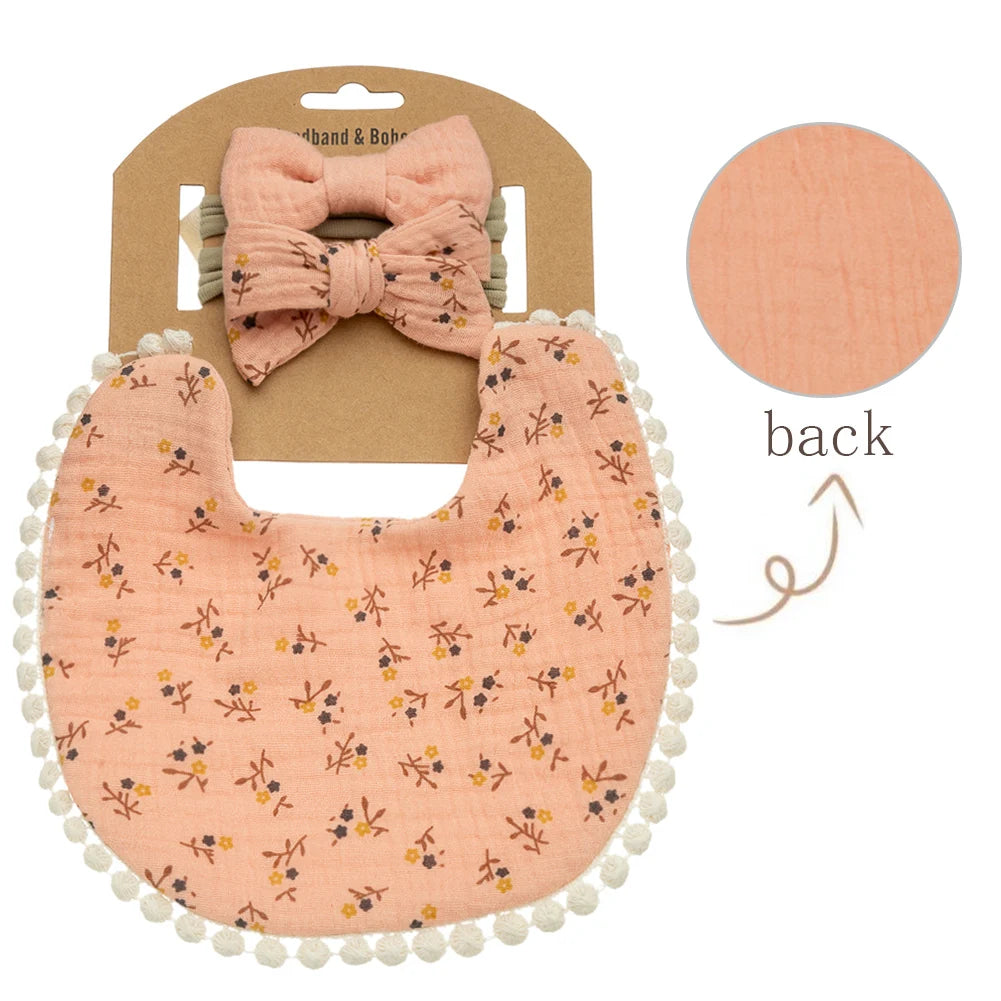 Vintage ditsy floral tiny petal print on apricot peach muslin baby girl bib with pom-pom fringe detailing.