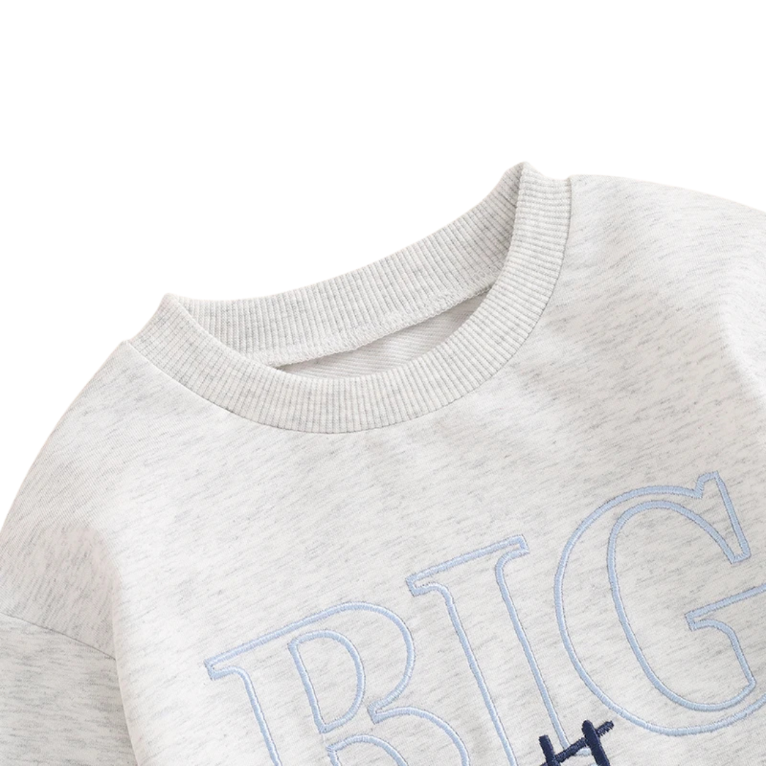 Close-up showing the classic ribbed crew neckline and top stitching on the light grey toddler boys Big Brother pullover.
