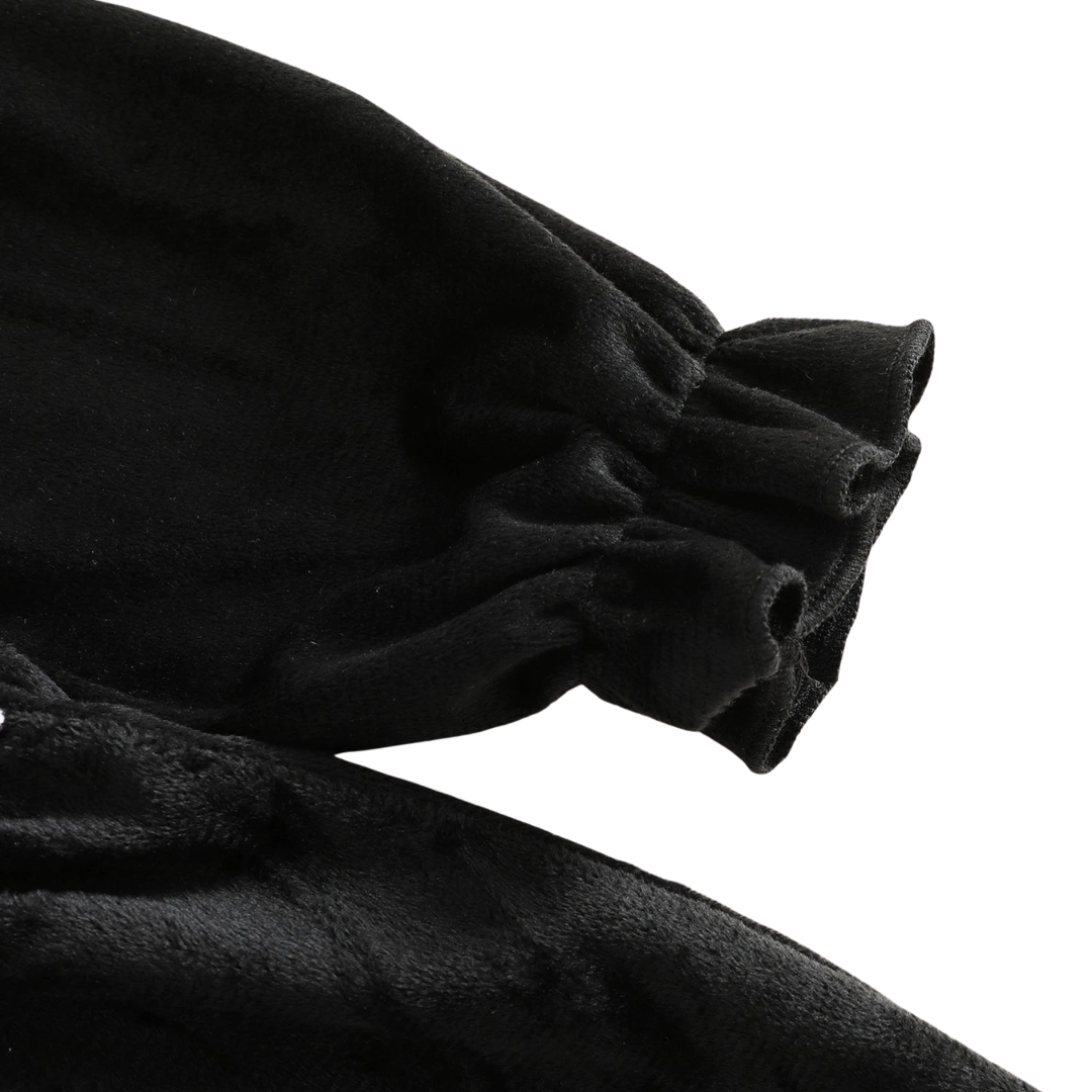 Close-up detail of the long sleeve featuring a gathered, elasticated ruffled cuff on the black smocked dress.