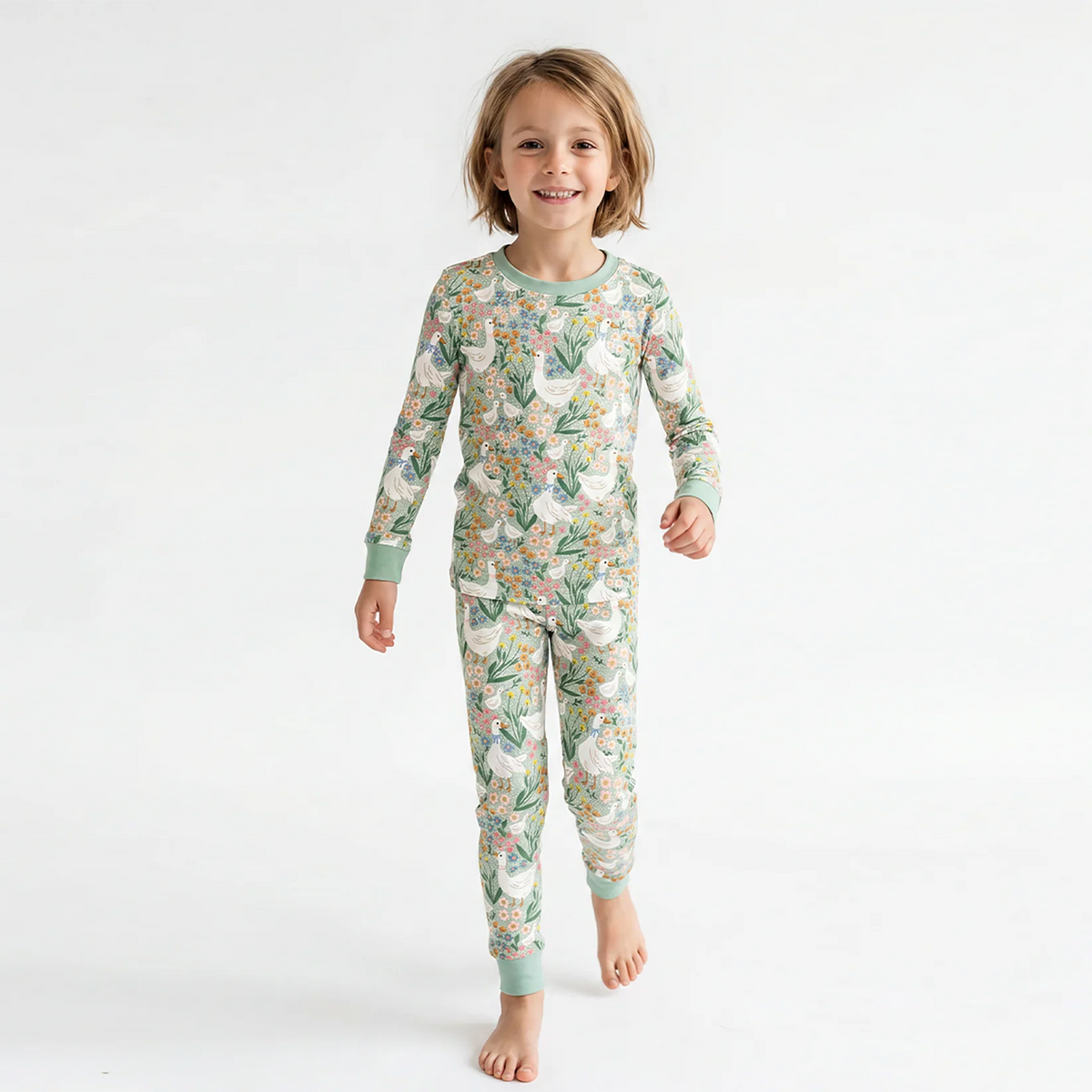 Toddler wearing two-piece farmhouse goose bamboo pajama set standing against a white studio backdrop