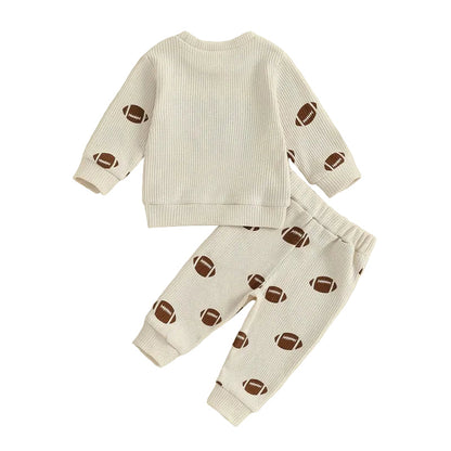 Back view flat lay of the two-piece toddler outfit showing the plain beige back of the waffle-knit pullover and the matching football print pants.