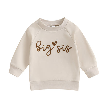 Clean flat lay of the cream-colored long-sleeve toddler sweatshirt with brown Big Sis graphic text.