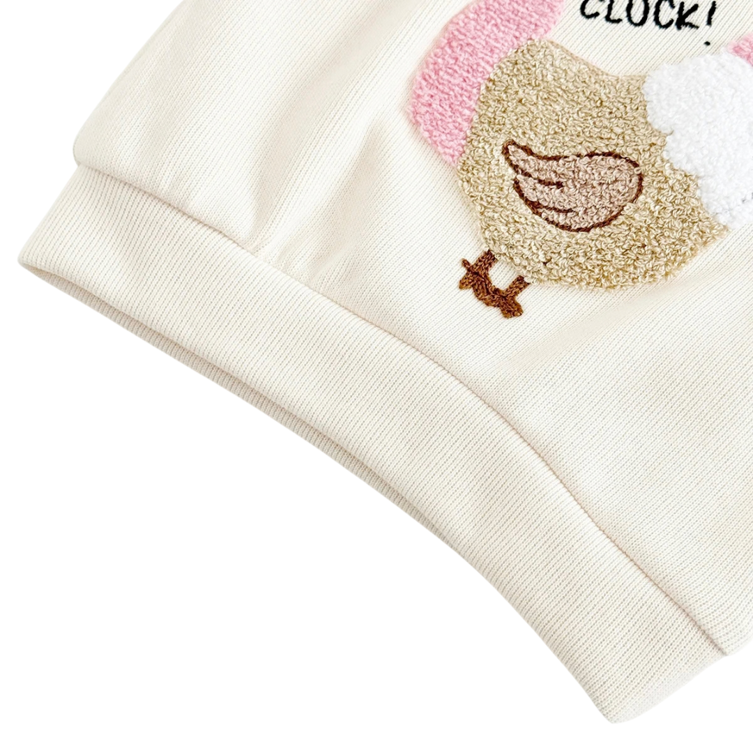 Close-up showing the textured chicken graphic embroidery and ribbed bottom hem of the baby girl pullover top.