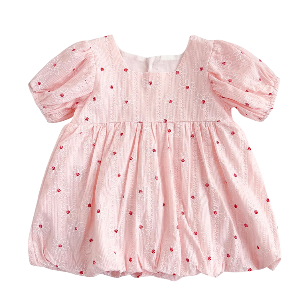 Vintage white baby girl bubble dress featuring red floral embroidery, puff sleeves, and a gathered hem on a neutral textured background.