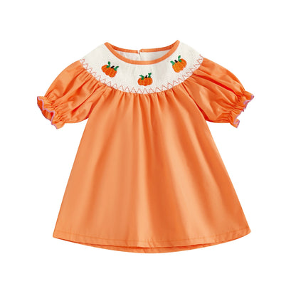 Solid orange smocked toddler dress featuring embroidered pumpkins along the neckline.