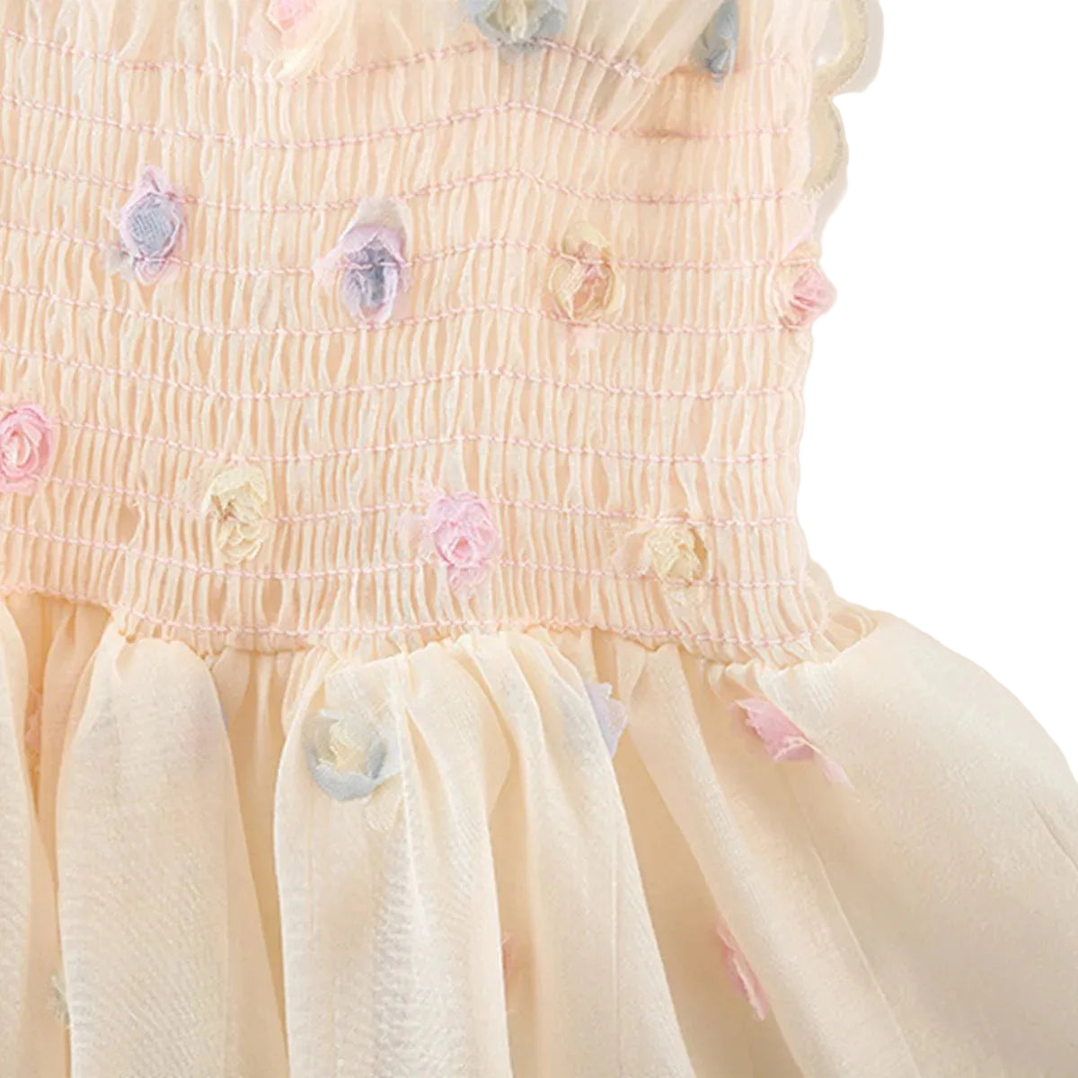 Close-up texture shot of the smocked waistline gathering and flowing chiffon overlay skirt featuring pink, blue, and yellow 3D floral appliqués.