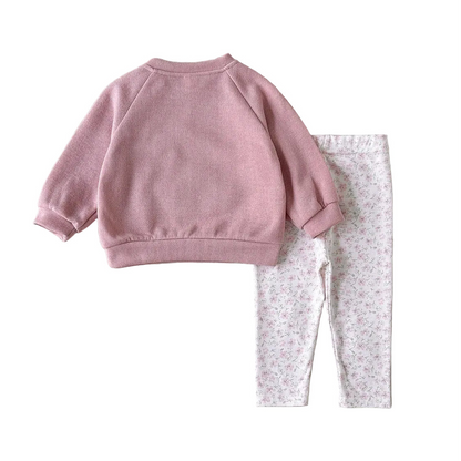 Flat lay arrangement showcasing the solid pink back view of the long-sleeve pullover sweatshirt alongside the full length of the patterned leggings.
