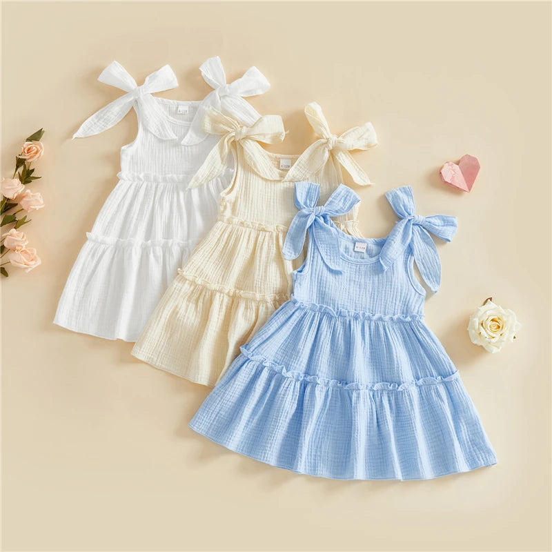 A collection of three little girls' tiered cotton cami dresses in Cloud White, Vanilla Cream, and Sky Blue.