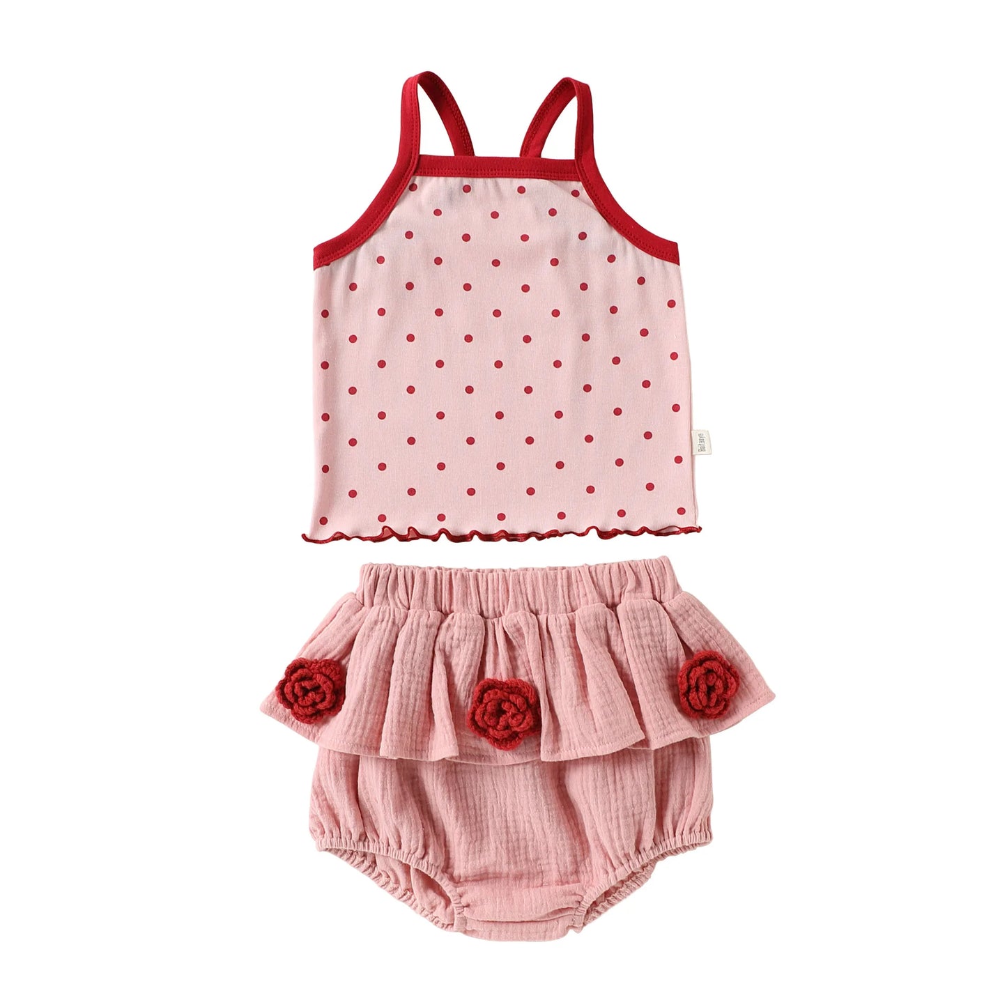 Front view flat lay of a toddler girl two-piece cotton summer set with a red-trimmed polka dot camisole tank top and pink ruffled bloomer shorts.