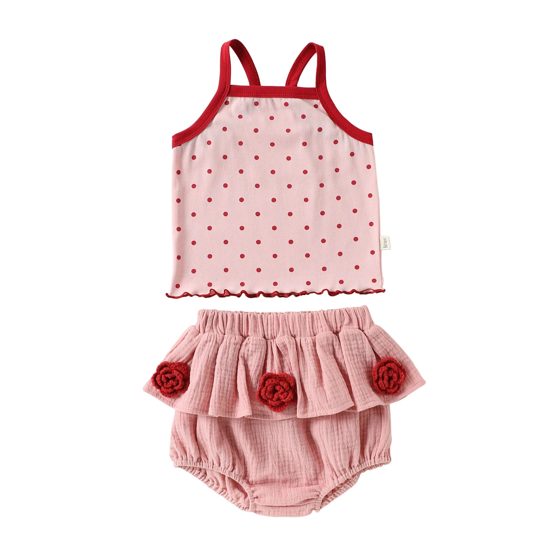 Front view flat lay of a toddler girl two-piece cotton summer set with a red-trimmed polka dot camisole tank top and pink ruffled bloomer shorts.