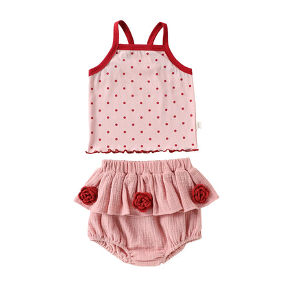 Front view flat lay of a toddler girl two-piece cotton summer set with a red-trimmed polka dot camisole tank top and pink ruffled bloomer shorts.
