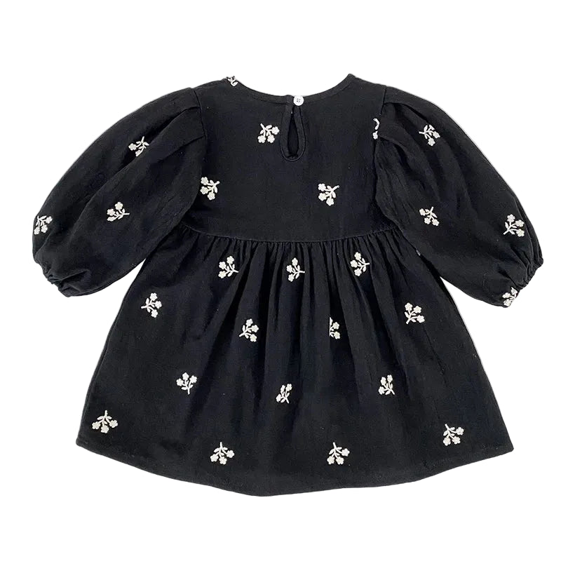 Full back view of the toddler girls black floral smock dress showing the keyhole closure and puff sleeves.