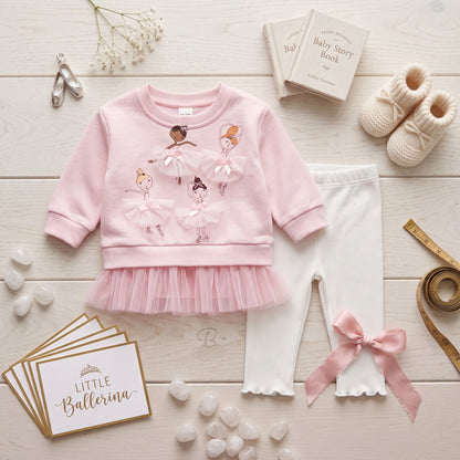 Flat lay view of baby girls pink ballerina ruffle sweatshirt set with white pants and accessories.