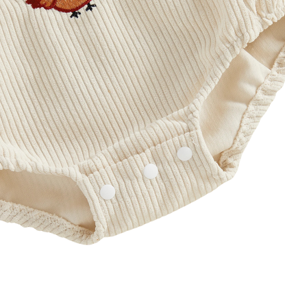 Close-up of the bottom snap closures for easy diaper changes on the beige baby corduroy bubble romper.