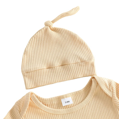 Close-up of the crew neckline of a beige ribbed baby romper and the matching newborn knot hat.