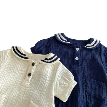 Stacked view of Sea Salt and Deep Sea rompers highlighting the contrasting nautical collars and muslin fabric.