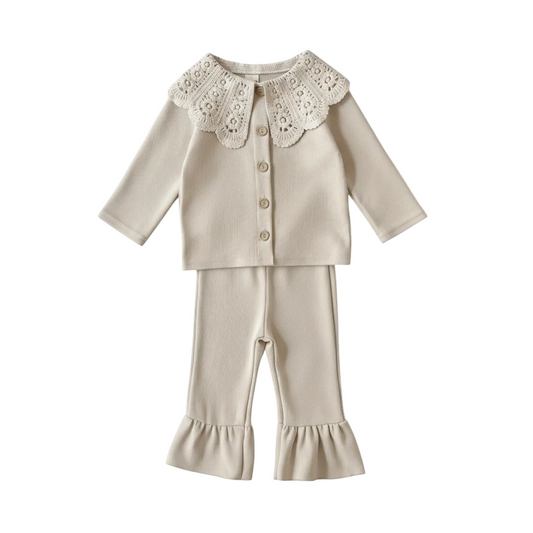 A two-piece baby girl's boutique clothing set in cream ribbed knit, featuring a long-sleeve cardigan with a large vintage-style white lace scalloped collar and matching flare-bottom leggings with ruffle cuffs, displayed on a clean white background.