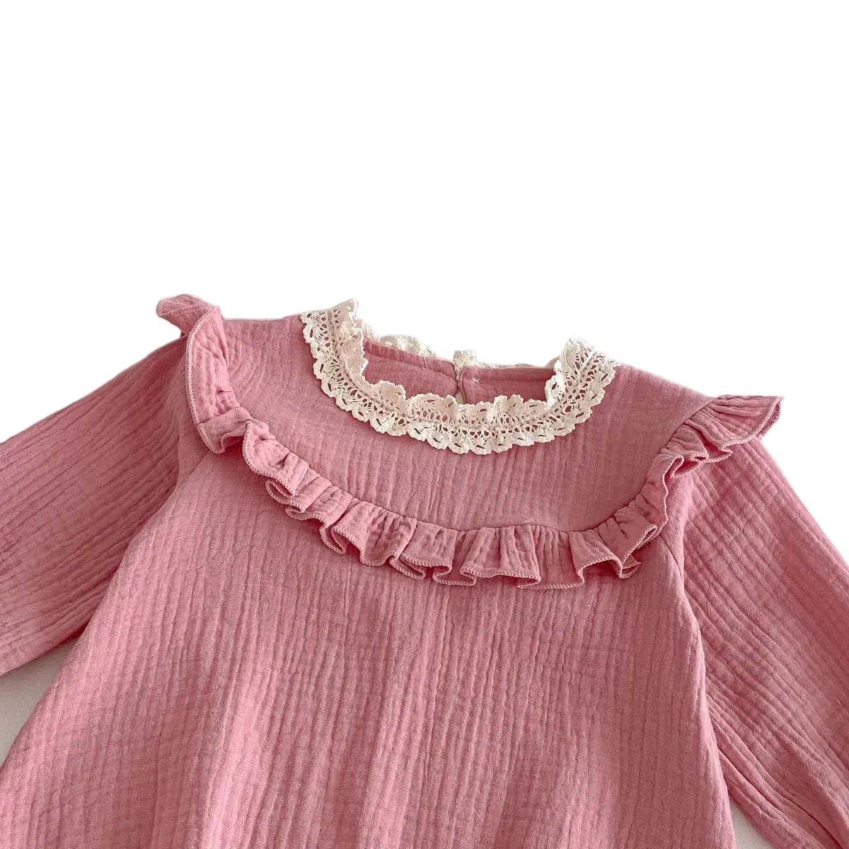 Close-up detail of the vintage white lace collar and pleated chest ruffle on a soft pink cotton muslin baby jumpsuit.