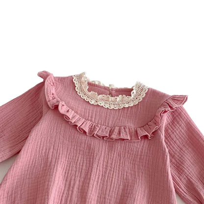 Close-up detail of the vintage white lace collar and pleated chest ruffle on a soft pink cotton muslin baby jumpsuit.