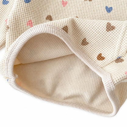 Close-up view of the soft cotton blend waffle knit material and elastic hemline of the heart print outfit