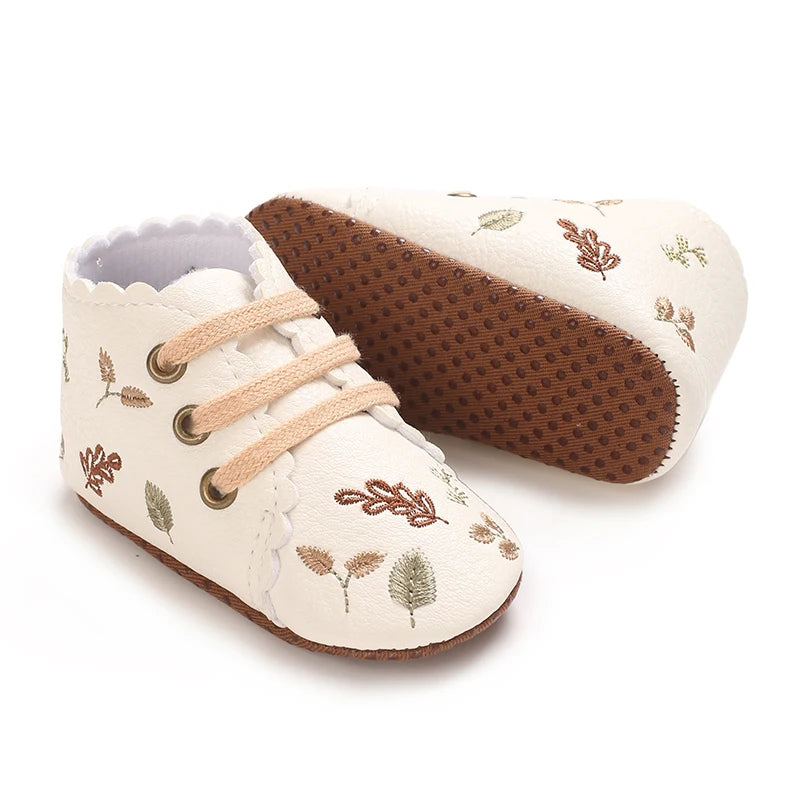 Soft anti-slip sole on white embroidered baby girl booties.